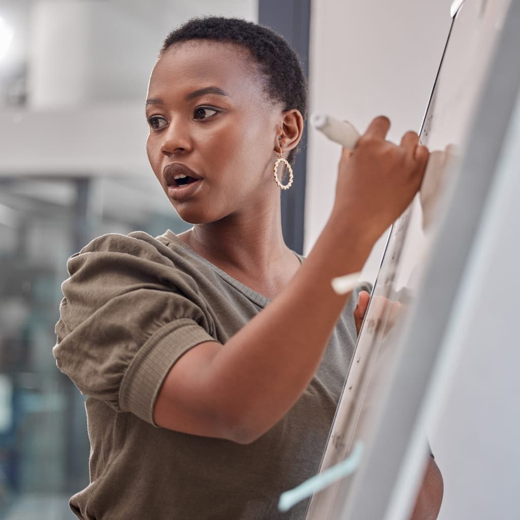Black woman writing on whiteboard